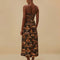back view of model wearing brown maxi dress with cutout front, tie halter neckline and burnt orange fan print