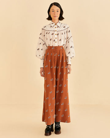 model wearing orange high waisted pants with pleats, button front and all over horse print