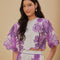 model wearing white top with purple abstract floral print and wavy hems