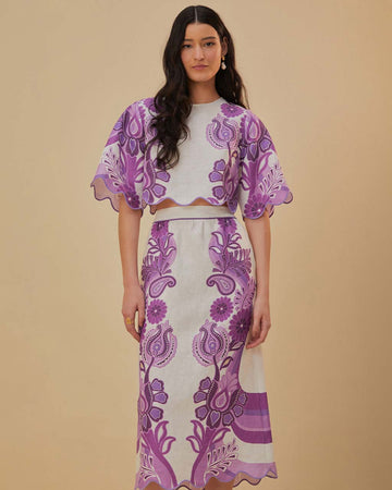 model wearing white midi skirt with purple abstract floral and wavy hem and matching cropped blouse
