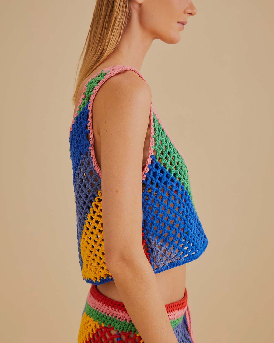 side view of model wearing open crochet cropped tank with diagonal rainbow stripes and matching skirt