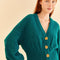 up close of model wearing emerald cardigan with fun tan floral buttons, balloon sleeves and ribbed waist