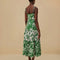 back view of model wearing green and white patchwork midi dress with tropical leaf print and tiered skirt