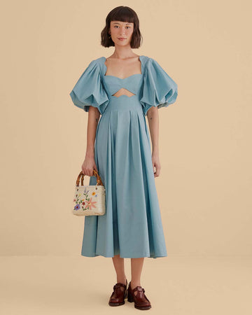 model wearing icy blue midi dress with scalloped cut out and exaggerated puff sleeves