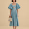 model wearing icy blue midi dress with scalloped cut out and exaggerated puff sleeves