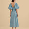 back view of model wearing icy blue midi dress with scalloped cut out and exaggerated puff sleeves