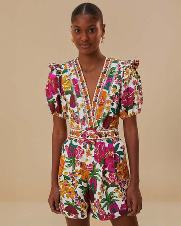 model wearing white romper with colorful floral print, puff sleeves, and belt detail