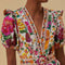 up close of model wearing white romper with colorful floral print, puff sleeves, and belt detail