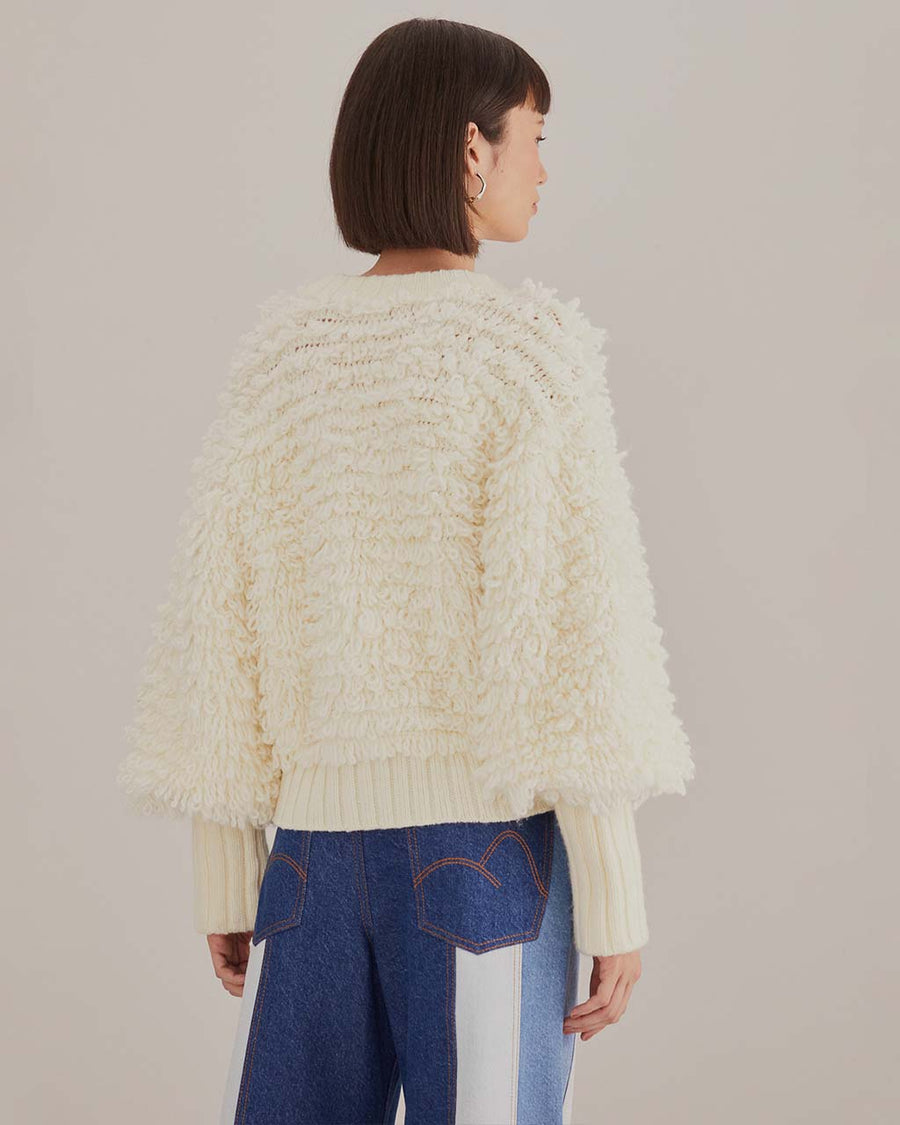 back view of model wearing textured off white slight cropped cardigan with with blouson sleeves 