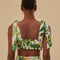 back view of model wearing white cropped tank top with tie straps, ruffle detail and green tropical leaf print