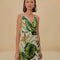 model wearing white mini dress with side button detail, v-neckline and green tropical leaf print
