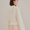back view of model wearing white sweater with puff sleeves and pearl detail