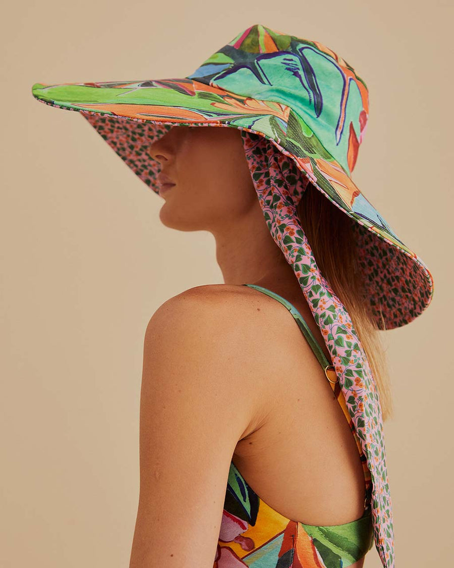 side view of model wearing wide brim sun hat with colorful abstract print and pink floral print