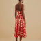 back view of model wearing red and cream abstract print dress with drop waist and bubble straps