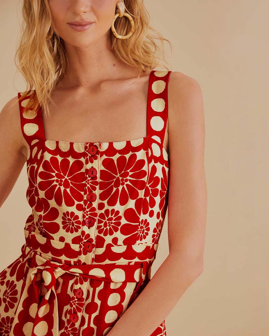 up close of model wearing cream and red abstract romper with tie waist and button front