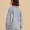 back view of model wearing light denim jacket with oversized collars and pink embroidered floral print