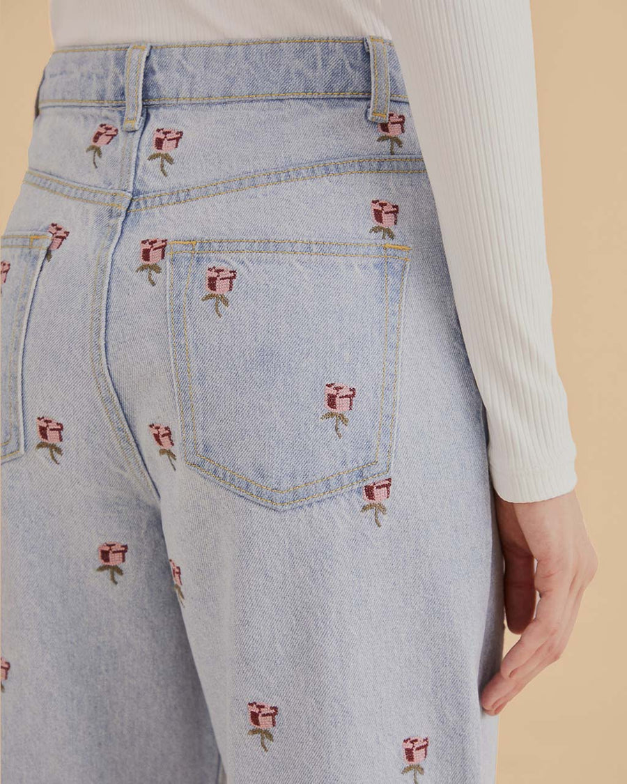 up close of model wearing wide leg light denim with embroidered pink flowers