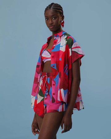 model wearing pink, red, and blue floral print shorts with tie waist and beaded tassels