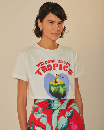 model wearing tucked white t-shirt with 'welcome to the tropics' and a coconut drink on the front