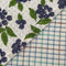 up close of set of two woven dishcloths: white with blueberry print and white with plaid in blue, green and burgundy