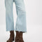 model wearing tall dark brown leather boots with silver buckle and strap detail around the ankle with light denim frayed jeans