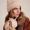 model wearing thick knit ivory winter hat with pom and fingerless gloves/mittens