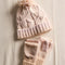 thick knit ivory winter hat with pom and fingerless gloves/mittens on a cream sheet