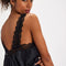 back view of model wearing black silky tank with black lace trim on the bust, straps and hem