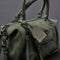 side view of olive green leather bag with two sets of straps and various zippers and zipper pulls