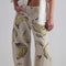 up close of model wearing tan barrel jeans with all over painted banana print