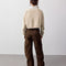 back view of model wearing dark brown vegan suede pants and oatmeal sweater