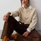 model wearing dark brown vegan suede pants and oatmeal sweater while sitting