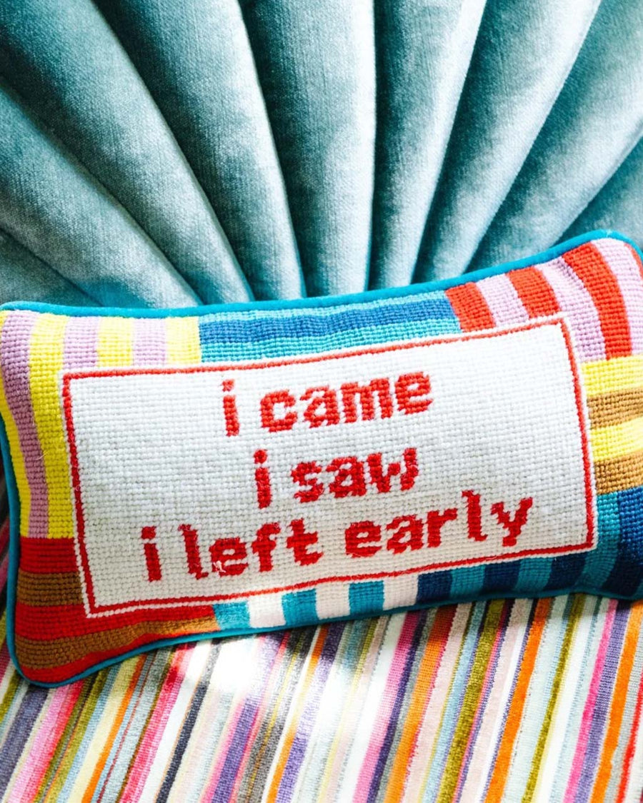 colorful striped rectangular throw pillow with 'i came, i saw, i left early' across the front on couch