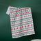 white tea towel with green and red holiday sweater print
