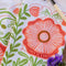 up close of white tea towel with abstract pink poppy print and greenery