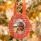 red, peach, and brown plaid round fabric frame ornament hanging from a tree