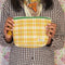 model holding yellow, burnt red and mint plaid quilted pouch with green print trim