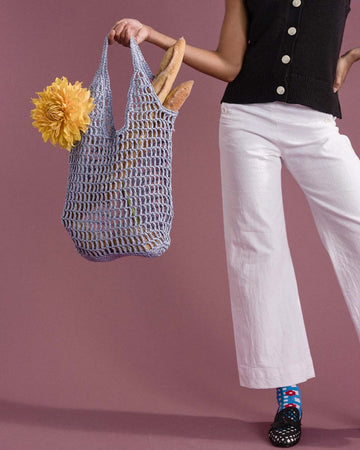 model holding fog paper crochet bag with bread and flower in it