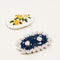 up close of set of two crochet hair clips: yellow flower and navy flower