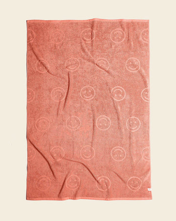 terra cotta colored plush towel with embossed smiley design