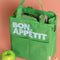 kelly green lunch bag with light blue 'bon appetit' across the front on a peach background