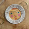 white trinket tray with sun face print and gold detail with a necklace on it