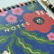 up close ofblue jotter notebook with red abstract floral print