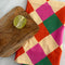 pink, orange, yellow and green diamond tea towel with a cutting board and lime on it