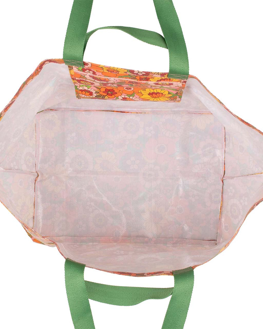 white interior of large beach bag with pink, yellow, and orange 70's inspired floral print and green strap