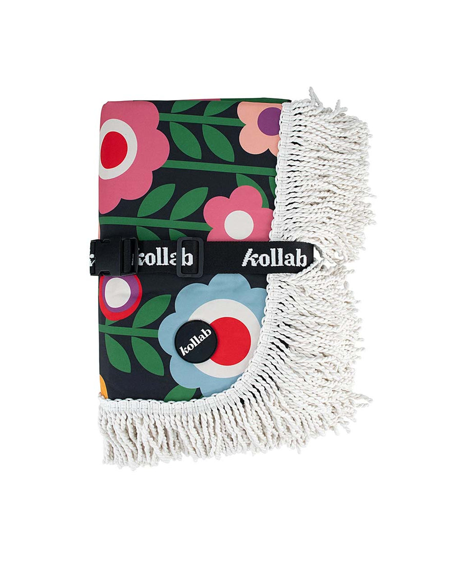 folded medium foldable picnic mat with colorful mod inspired floral print and white fringe