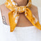 model wearing golden yellow 22 in. x 22 in. square bandana with white floral print knotted in the front