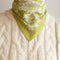 model wearing yellow/green 22 in. x 22 in. square bandana with white floral print with knot in the back