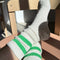 up close of model wearing white crew socks with two kelly green stripes on the top