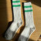 white crew socks with two kelly green stripes on the top